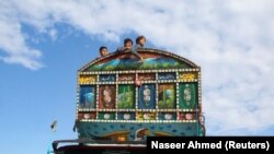 په چمن کې درې ماشومان په لارۍ کې سپاره دي او افغانستان ته د اوښتو په انتظار دي - د نومبر اتمې انځور.