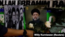 د مې پر ۲۰مه په جکارته کې د ايران د سفارت مخې ته خلګ د رييسي د عکس مخې ته ګلونه ږدي.