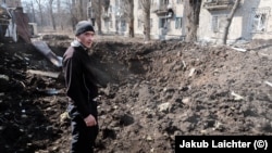 Чоловік в Авдіївці оглядає свіжу вирву в центрі його рідного міста після російського обстрілу. Фото: Якуб Лайхтер (©)
