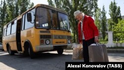 Egy nő táskákat cipel, miközben evakuálják Novaja Kahovkából, a kahovkai gát átszakadása nyomán keletkezett áradás elől
