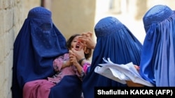 په افغانستان کې ښځينه واکسيناتورانې ماشومانو ته پوليو ضد څاڅکي ورکوي ـ پخوانی انځور