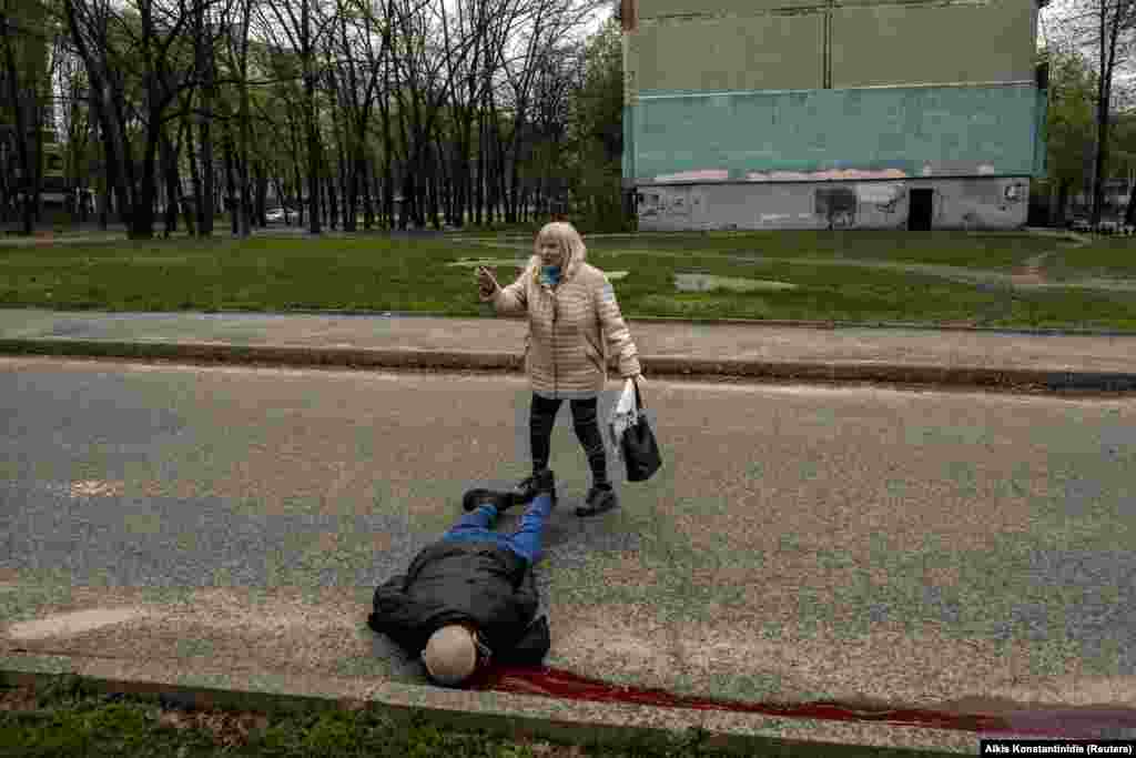 Женщина у тела мужчины, погибшего во время обстрела жилого массива в Харькове 19 апреля 