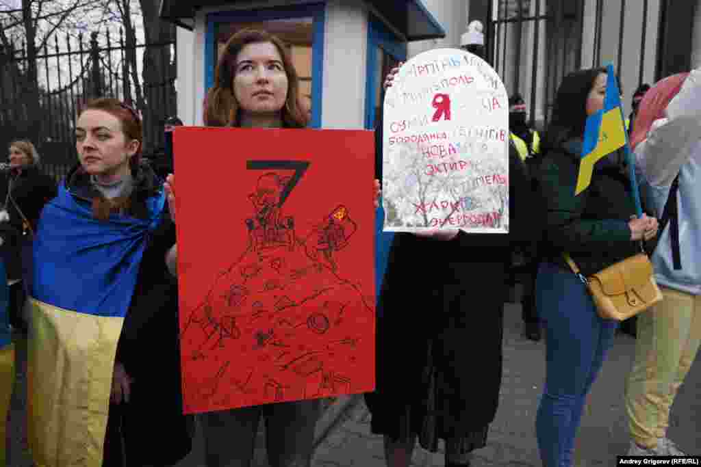 Участница молчаливого протеста. В руках одной из них — плакат с названиями населенных пунктов, пострадавших от российской оккупации или нападения