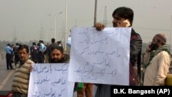 Supporters of a Pakistani religious group protest holding placards read "hang blasphemous Asia," as they blocked the main road to Islamabad on October 31.
