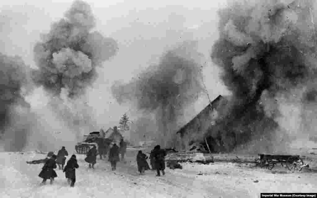 Солдаты Красной армии при поддержке танка Т-34 продвигаются через деревню во время масштабного контрнаступления против нацистских захватчиков. Хотя многие историки считают осень и зиму 1941–42 годов началом конца гитлеровского вторжения в Советский Союз, человеческие страдания тогда только начинались.