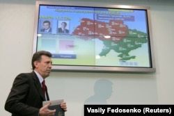 Șeful Comisiei Electorale Centrale din Ucraina, Serhi Kivalov, trece pe un ecran cu rezultatele preliminare ale turului doi al alegerilor prezidențiale la începutul zilei de 22 noiembrie 2004.