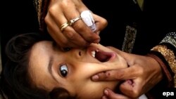 یو روغتیايي کارکوونکی ماشوم ته د ګوزڼ واکسیني څاڅکي ورکوي