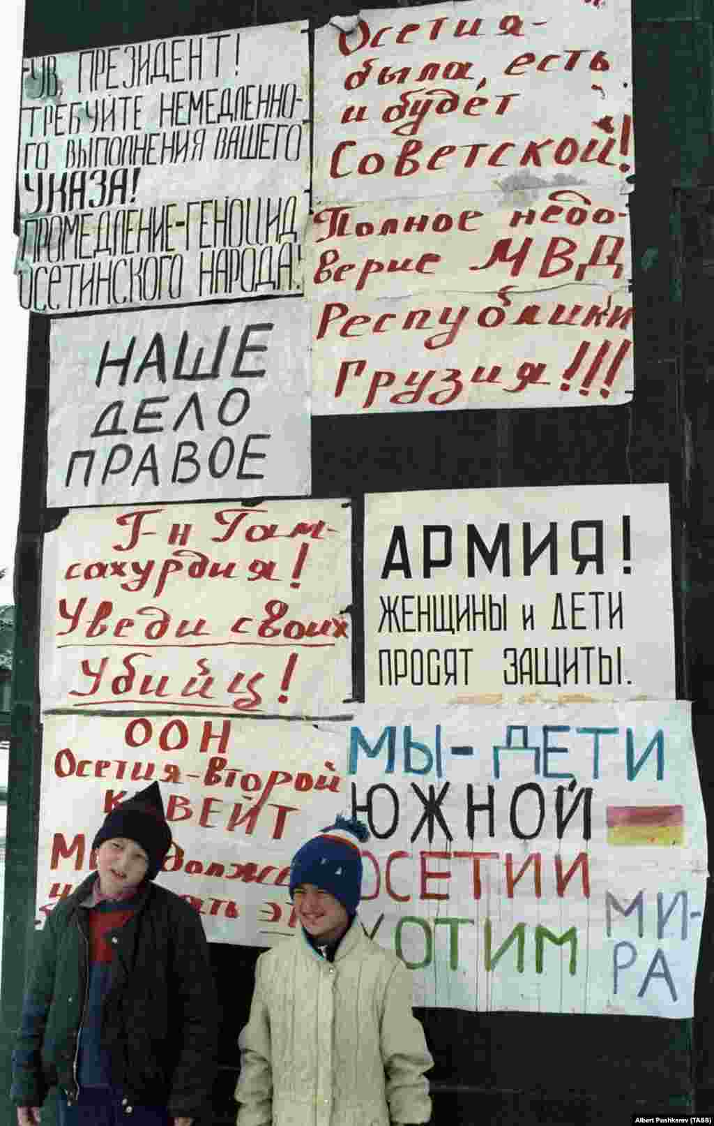 Діти в Цхінвалі 1 січня 1991 року позують поруч із плакатами на пам'ятнику Леніну, який осетини не дозволили знести. На одному з плакатів написано: «Осетія була, є і завжди буде радянською!» Багато грузинів вважали етнічних осетин зрадницькою «п'ятою колоною» в той час, як їхня країна боролася за свободу від Радянського Союзу. А осетини відчували себе відстороненими від нових законів, які зробили грузинську мову єдиною офіційною мовою країни і перешкоджали політичному представництву осетин в Тбілісі
