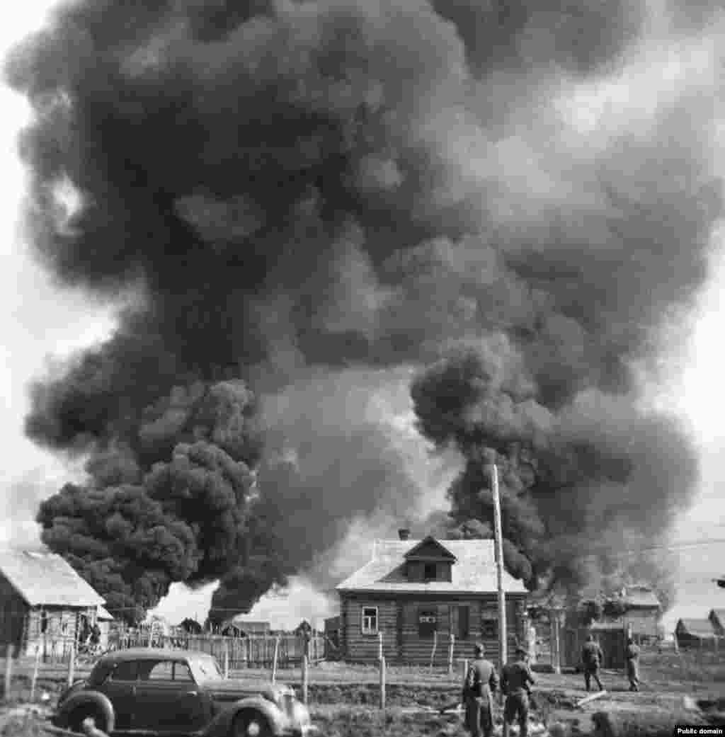 Немецкие солдаты смотрят, как горит советская деревня, июнь 1941 года. Операция «Барбаросса» была крупнейшим военным наземным вторжением в истории: около 3,8 миллиона солдат, тысячи танков и самолетов и более полумиллиона лошадей выдвинулись через всю Восточную Европу, от Финского залива до Черного моря.