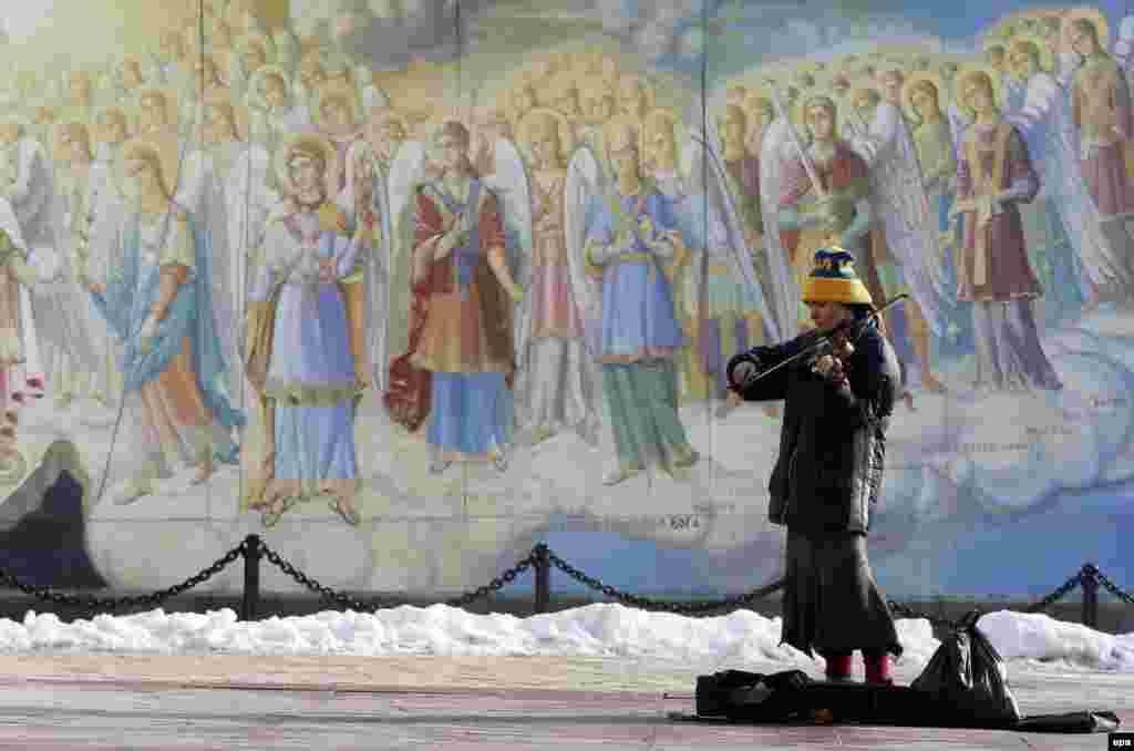 Молода жінка-музикант грає на скрипці перед Михайлівським собором у центрі Києва, 17 січня 2017 року