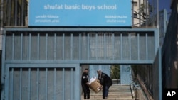 Učenik i nastavnica nose nastavni materijal u školi za dječake UNRWA-e u izbjegličkom kampu Šuafatu u istočnom Jerusalemu, 8. maja 2025.