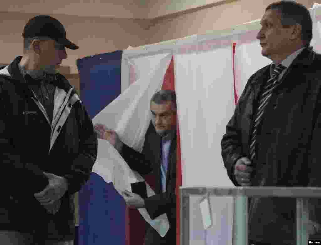 Қырым премьер-министрі Сергей Аксенов сайлау учаскелерінің біріндегі дауыс беру кабинасынан шығып келеді.