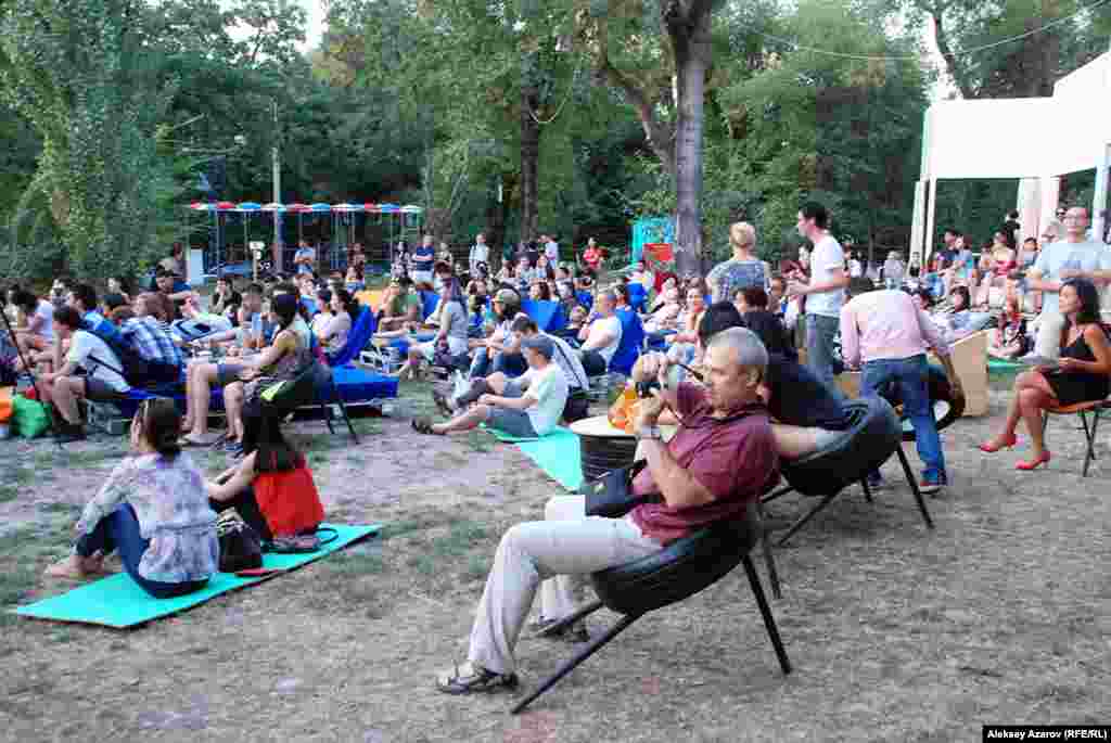 Мұндағы орындықтар ескі көлік дөңгелектерінен жасалған. Кейбір адамдар туристік кілемшелер үстінде отырды. 