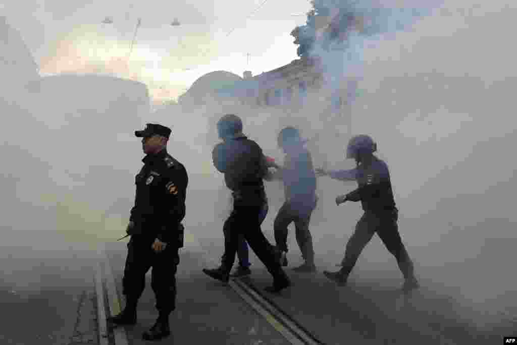 A protester is led away through clouds of smoke in St. Petersburg. 