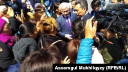 Еңбек және халықты әлеуметттік қорғау министрі Бердібек Сапарбаев (ортада) пен Нұр-Сұлтан әкімі Бақыт Сұлтановтың наразылыққа шыққан аналар ортасына келген сәті. Нұр-Сұлтан, 16 мамыр 2019 жыл.