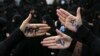 Hard-line Iranian protesters show their hands with writing in Persian that reads, "No to FATF," to protest the passage of a bill which joins Iran to the "Combating the Financing of Terrorism" on October 7.