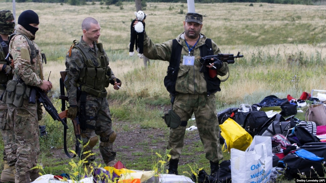 Бойовик російських гібридних сил тримає іграшку, виявлену на місці падіння уламків «Боїнга», збитого російською установкою «Бук», в результаті чого загинуло 298 людей, в тому числі 80 дітей. Донеччина, неподалік села Грабове, 19 липня 2014 року