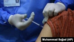 په پېښور کې یو روغتیاپال یو کس ته د کووېډ-۱۹ واکسینو ستن لګوي - انځور له ارشیفه