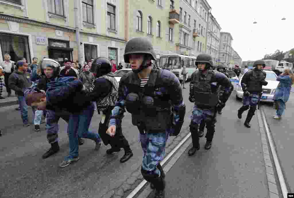 Police wearing ballistic helmets advance up a street in St. Petersburg. 